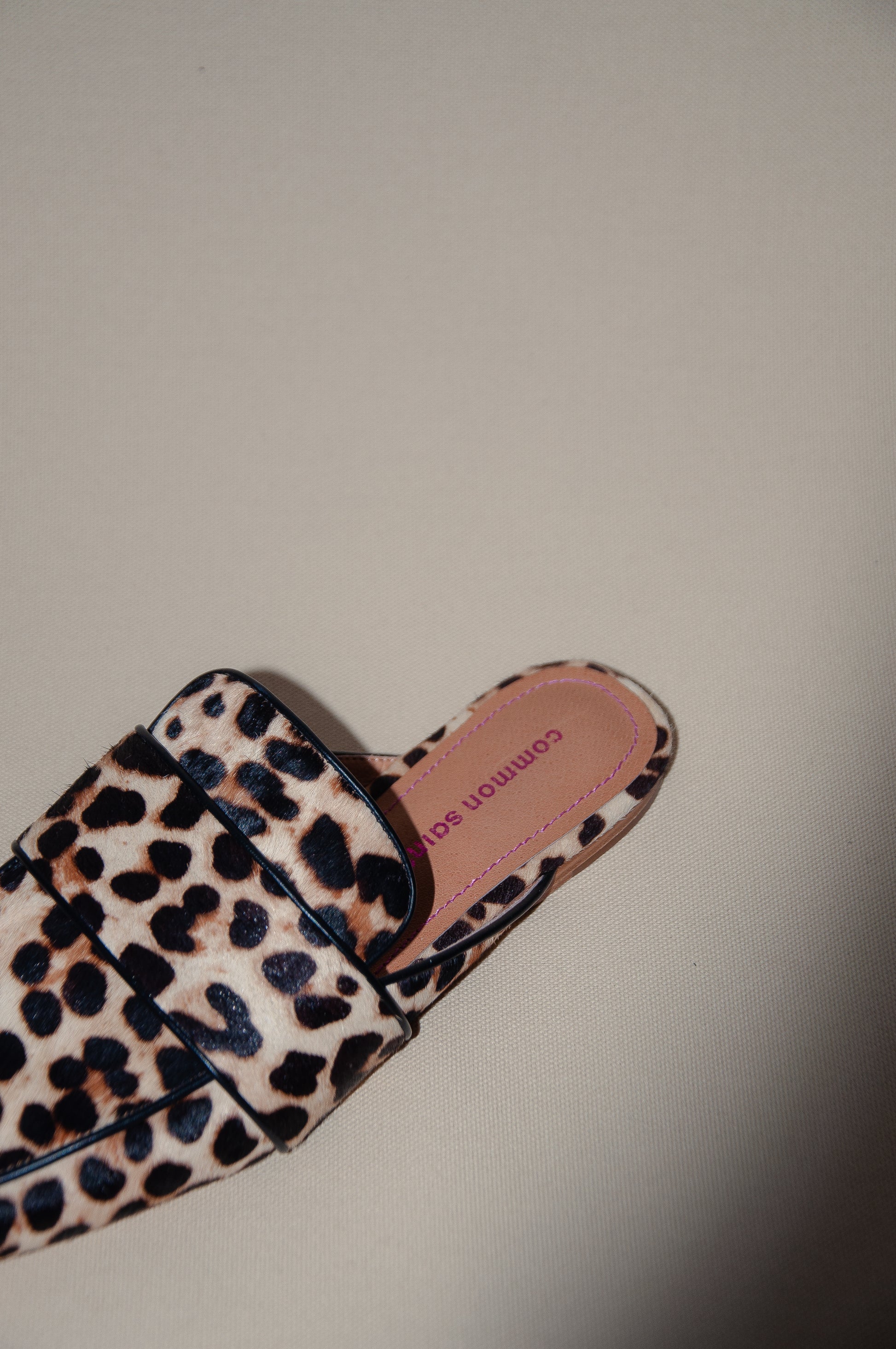 A left luxury leopard print slip on mule with piping detail on edge