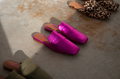 A line up of 3 pairs of common saint slip on mules, set on a diagonal line.  Bottom left is a khaki mule, The metallic pink is set in the middle and leopard print on the top right.  The major mule has a soft square toe.  There is shadow casting on the photo and is set on a concrete floor.  